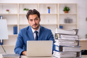 Young male employee and too much work in the office