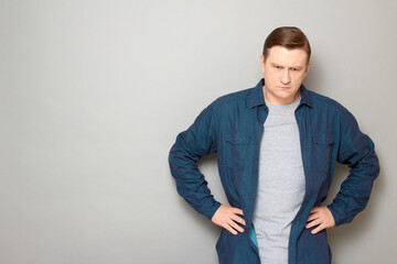 Portrait of sad disappointed man holding hands on hips and thinking
