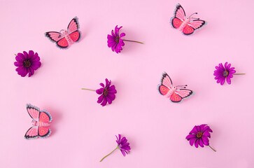 A wallpaper or pattern made of butterflies and spring flowers against pink background. Creative concept for web banner, invitation or phone background
