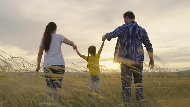 Dad, mom, daughter run, jump on fence in field. Happy family runs in park, sunset. Happy girl kid is playing in park. Childrens games with parents, teamwork. Playing, kid people outdoors. Little girl
