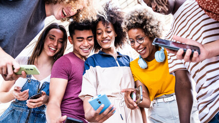 Diverse teenage students using digital smart mobile phones on college campus - Group of friends...