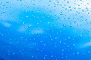Raindrops on a blue car, close-up. Lots of water drops on blue paint. Calming background, element for design. Blank for design or wallpaper