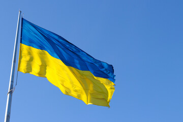 The national flag of Ukraine flutters in the wind against the blue sky. National symbol. Freedom and patriotism. Copy space