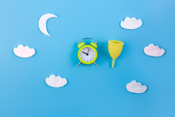 Silicone menstrual cup with moon, clouds flatlay on blue background. Women's health and alternative...