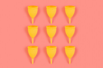 Menstrual yellow cups pattern on a pink background. Monochrome zero waste concept. eco-friendly, Alternative reusable product for female hygiene.