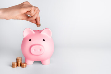 Human hand putting coins in piggy bank. Money saving concept.