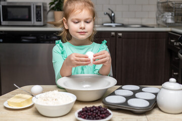 Little girl cooking in kitchen. Child sitting at table with food. Kid baking at home