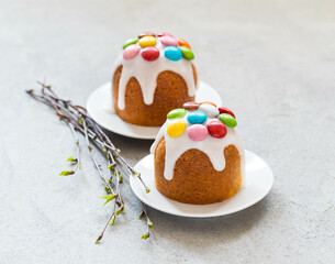 Easter cake with icing sugar, decorated with colorful dragees, on a plate. Light grey background