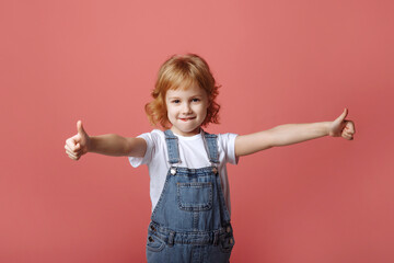 Cheerful little girl jumping on a pink background.