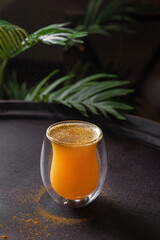 Tropical drink with curry spice on dark table