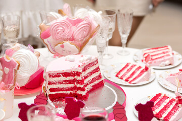 Cut pink-red velvet cake, around the plates pieces of cake, baby shower party.