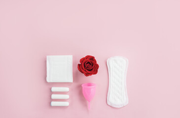 Alternative types of intimate feminine hygiene and red rose. Сoncept of women's periods. Selective focus, copy space