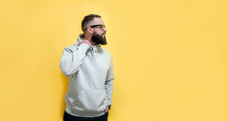 Studio portrait of handsome hipster guy with beard wearing gray blank hoodie with space for your...