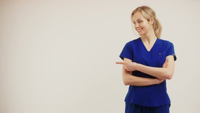 Copy space white background female doctor surgeon looking aside and pointing with her finger and crossing her arms. High quality 4k footage