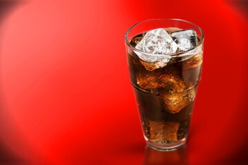 caramel drink, no cola, with ice. Fresh cold sweet drink with ice cubes on red background.