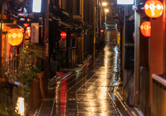 Red lanterns line wet alleyway in Kyoto at night