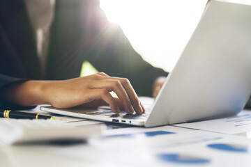 Close up Businessman hand holding pen and pointing at financial paperwork, financial charts to analyze profit concept