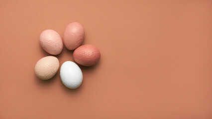 Group of neutral colored Easter eggs with pretty texture  on minimal brown earth tone background. Minimal holiday concept, top view, copy space. Happy Easter card.