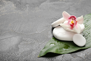 Spa stones with orchid flower and tropical leaf on dark background