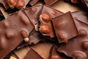 Pieces of tasty chocolate with nuts on board, closeup