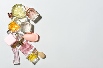 Bottles of different perfumes on light background, top view