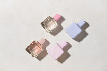 Bottles of different perfumes on light background, top view