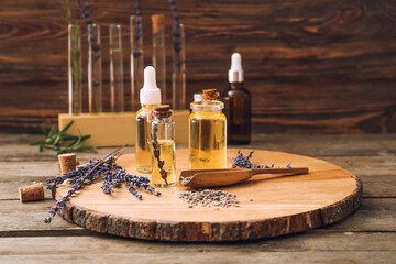 Bottles of natural lavender essential oil on wooden background