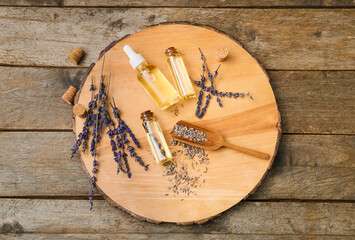 Bottles of natural lavender essential oil on wooden background