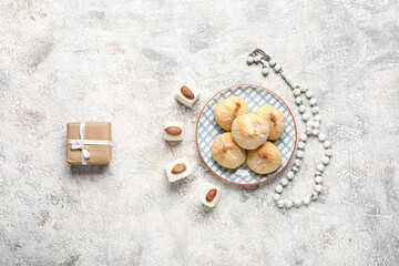 Fototapeta na wymiar Tasty Eastern sweets with gift and tasbih on grunge background