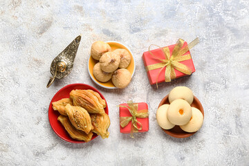Tasty Eastern sweets with gifts and Aladdin lamp on grunge background