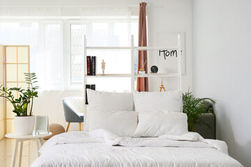 Interior of light bedroom with white bookcase