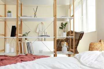 Interior of light bedroom with book shelves and bathtub