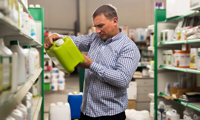 Man buying liquid fertilizer for gardening in hypermarket