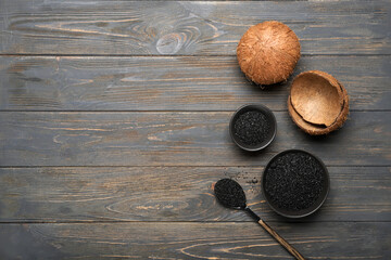 Bowls with coconut activated carbon on dark wooden background