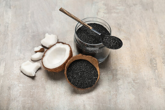 Jar and coconut shell with activated carbon on grey background