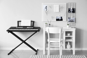 Modern synthesizer and workplace with peg board on wall in room