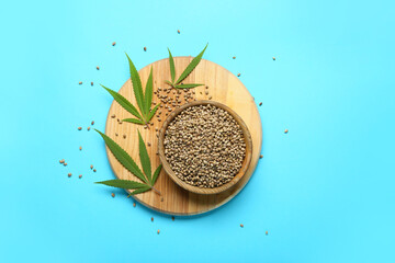 Bowl with hemp seeds on color background