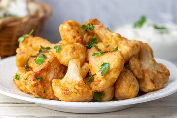 Fried in batter Cauliflower florets served on a black plate on a grey concrete table with ingredients, view from above, close-up, flatlay, copy space