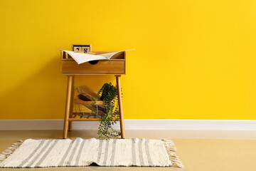Obraz premium Wooden bedside table with decor near yellow wall