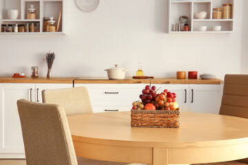 Fruit basket on wooden table in light kitchen