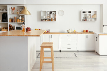 Fototapeta na wymiar Interior of light modern kitchen with white counters, shelves and food