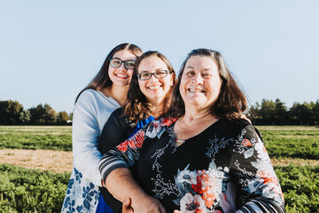 Grandmother, mother and daughter smiling in the middle of the field on a sunny day afternoon. Family portrait.