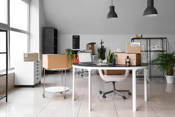 Cardboard boxes with belongings and furniture in interior of office on moving day