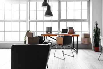Cardboard boxes with belongings and furniture in interior of office on moving day