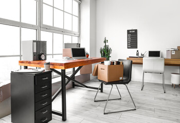 Cardboard boxes with belongings and furniture in interior of office on moving day