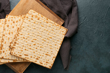 Board with Jewish flatbread matza for Passover and napkin on dark background