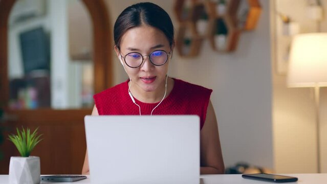 Young Asian woman talking on video call conference or virtual meeting at home via laptop