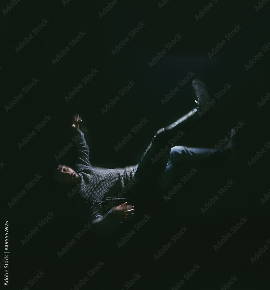 Wall mural falling your dream thats fear of losing control. shot of a young man falling against a dark backgrou