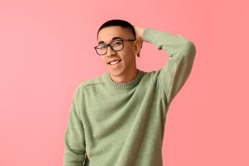 Handsome young Asian man in knitted sweater on pink background