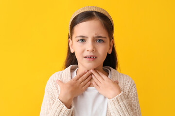 Little girl suffering from sore throat on yellow background
